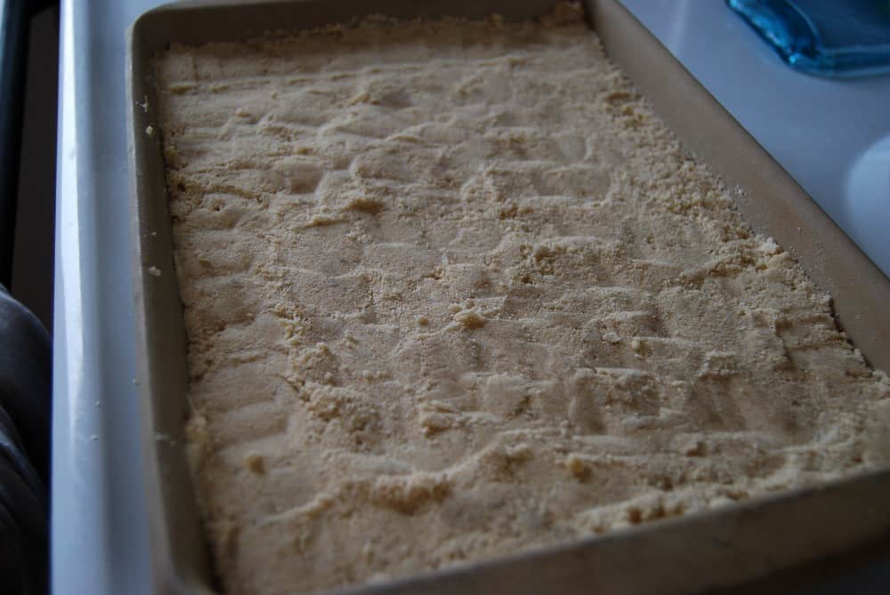 Shortbread crust in a baking dish for toffee bars.