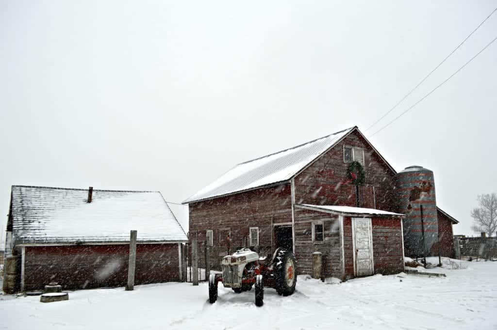 Winter Wonderland around a barn and tractor.