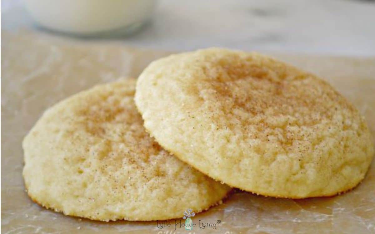 Soft sour cream cookies on parchment paper with milk in the background.