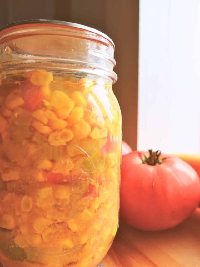 Corn Relish in a jar next to a ripe tomato.