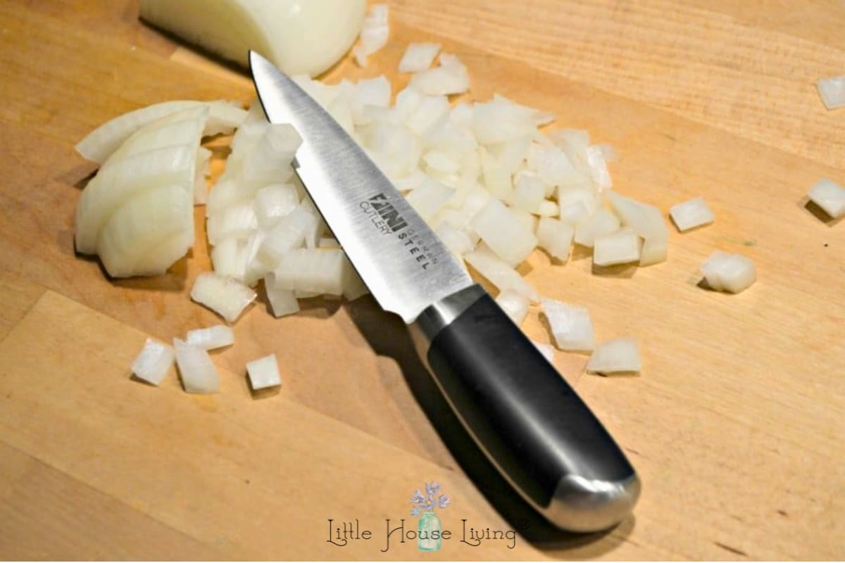 a knife with chopped onions on a cutting board