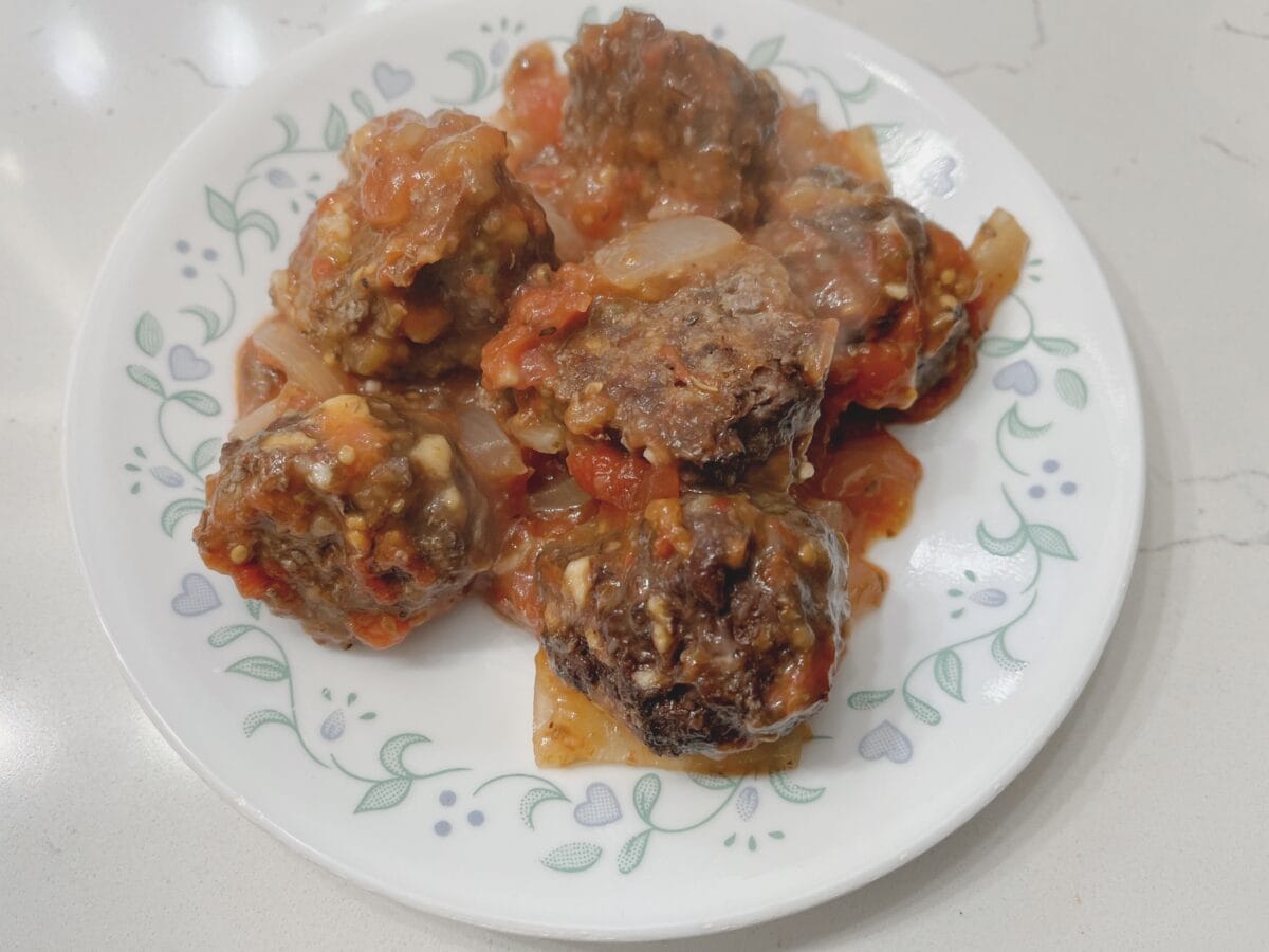 tomato gravy over meatballs on a floral plate