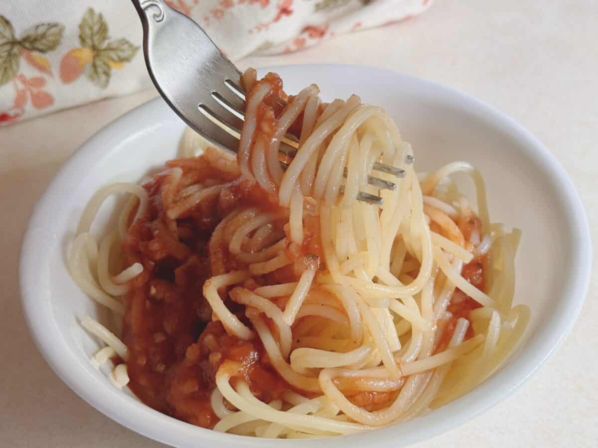 Delicious homemade spaghetti with tomato gravy, served in a white bowl for comfort food.