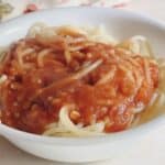 Delicious spaghetti topped with flavorful tomato gravy in a white bowl. Perfect comforting meal for dinner.
