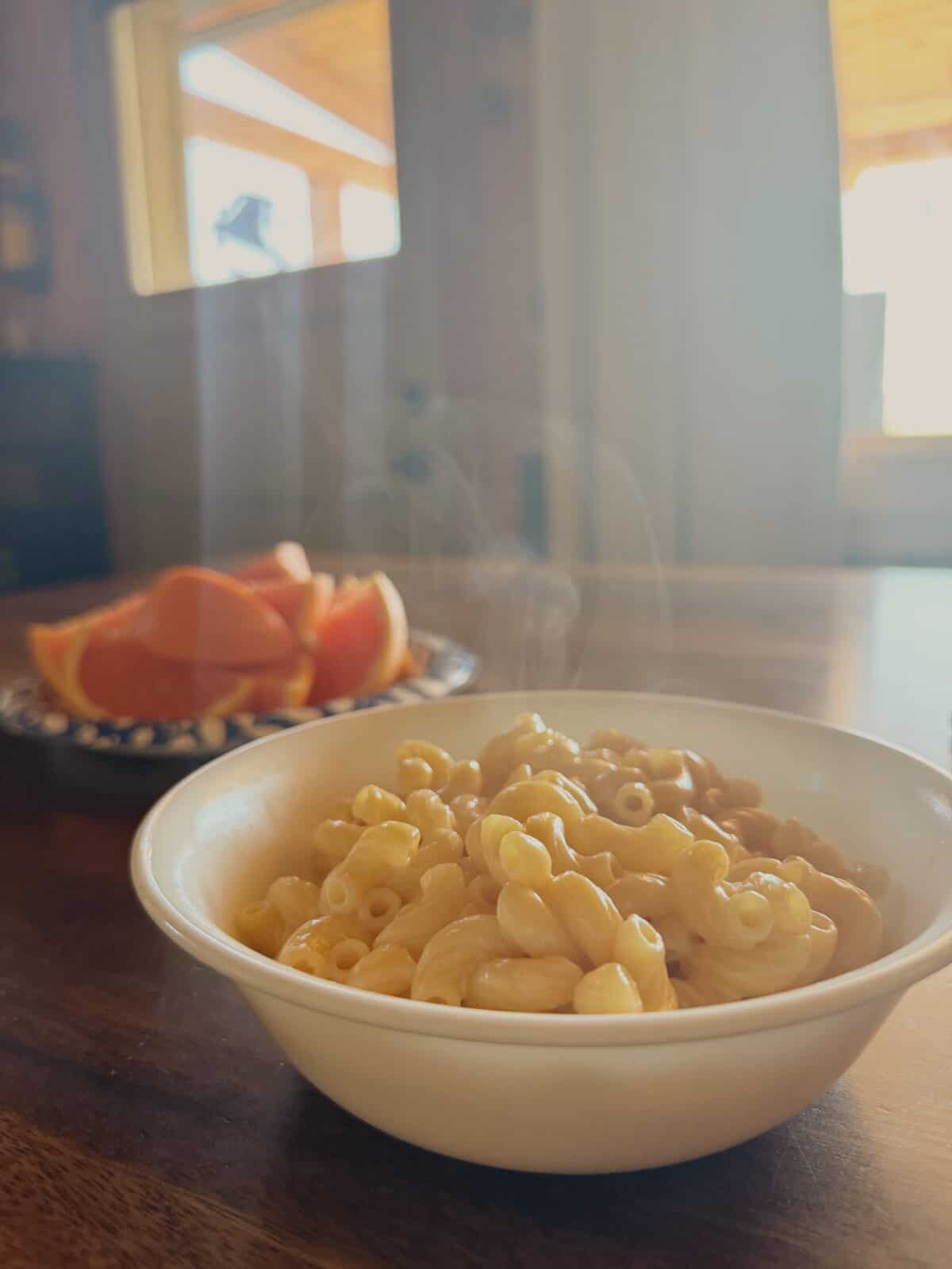 mac and cheese in a bowl with oranges in the background